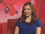 Alyson interviewée assise sur un canapé rouge